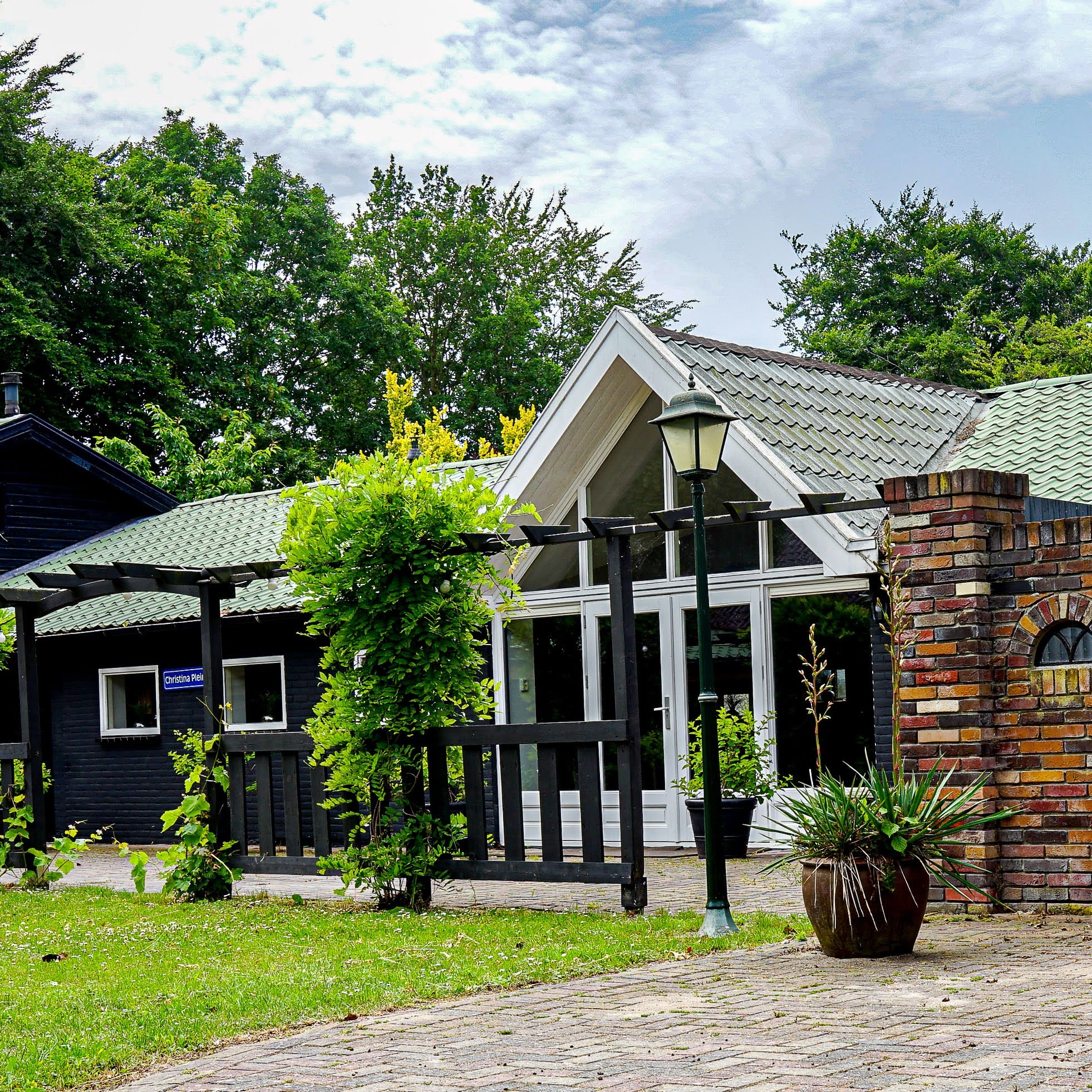 Entree van de Grote Zaal met pergola, klimplanten en bakstenen gevel met rondboograampjes