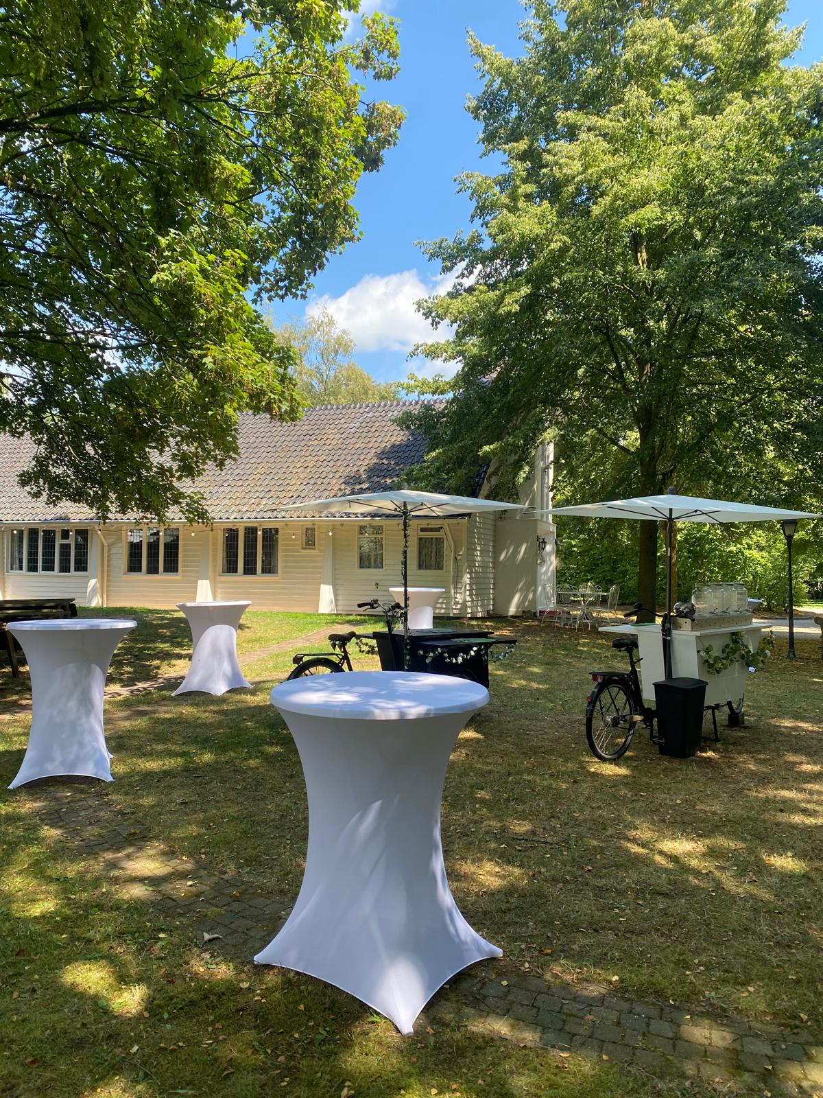 Statafels met witte rokken in de tuin van Wit Kerkje, klaar voor een zakelijke borrel